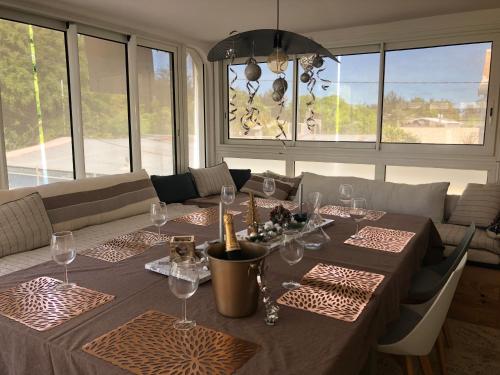 ein Esszimmer mit einem Tisch und Weingläsern in der Unterkunft Le Pelican in L'Ermitage-Les-Bains