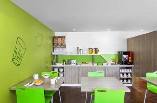 a kitchen with green walls and wooden tables and chairs at ibis Budget - Newcastle in Newcastle