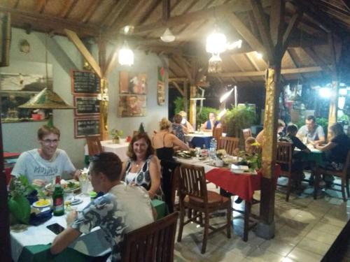 a group of people sitting at tables in a restaurant at Barclona Guesthouses Lovina in Pabean Buleleng