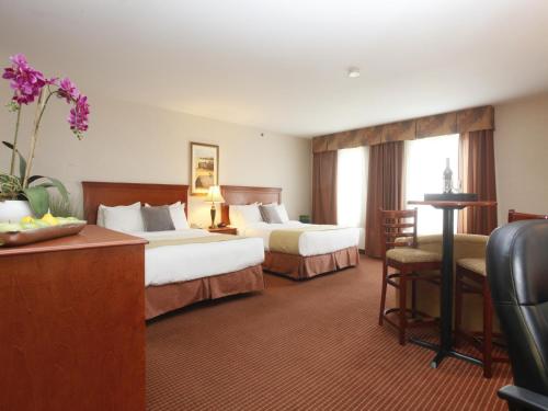 ein Hotelzimmer mit 2 Betten und einem Tisch in der Unterkunft Stonebridge Hotel Dawson Creek in Dawson Creek