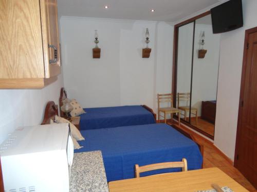 a room with two beds and a kitchen with a table at Ria Studios in Olhão