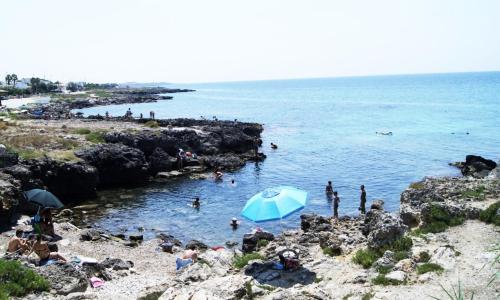 a group of people on a beach with a blue umbrella at Vistamare in Alliste