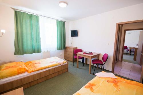 a hotel room with two beds and a table and chairs at Penzión Krahule in Kremnica