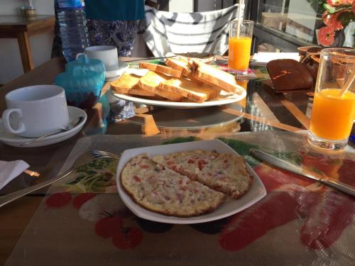 un tavolo con piatto di cibo, pane e succo d'arancia di Chez Allen a Nuwara Eliya