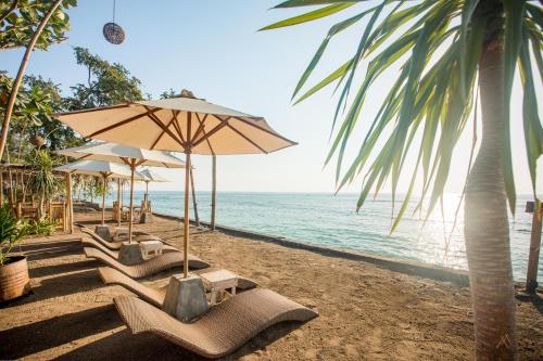 - une plage avec des chaises et des parasols et l'océan dans l'établissement Bambu Cottages, à Gili Air