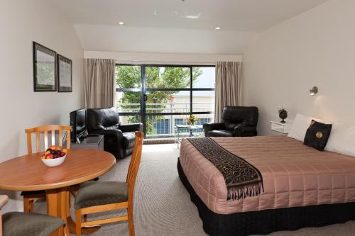 a bedroom with a bed and a table and chairs at Country Glen Lodge in Christchurch