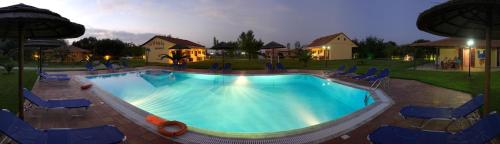 una gran piscina con sillas azules y una casa en Villagio, en Lefkada