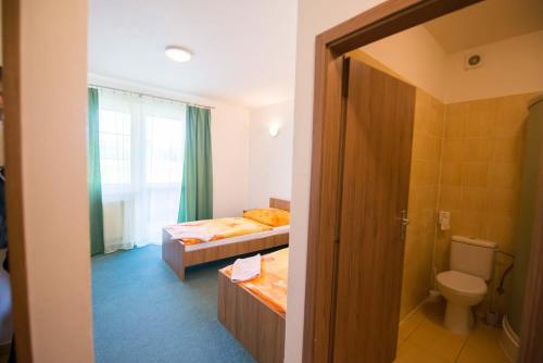 um quarto com 2 camas, um WC e uma janela em Penzión Krahule em Kremnica