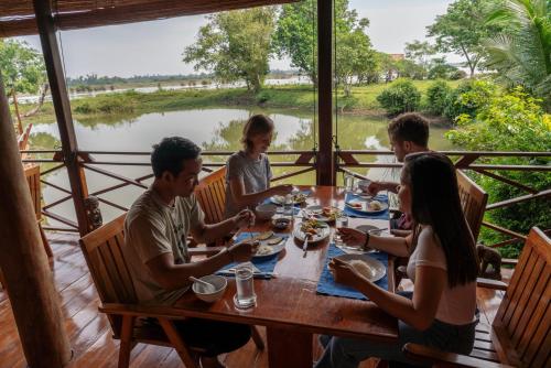 a group of people sitting around a table eating food at Kingfisher Ecolodge in Ban Kian-Ngông