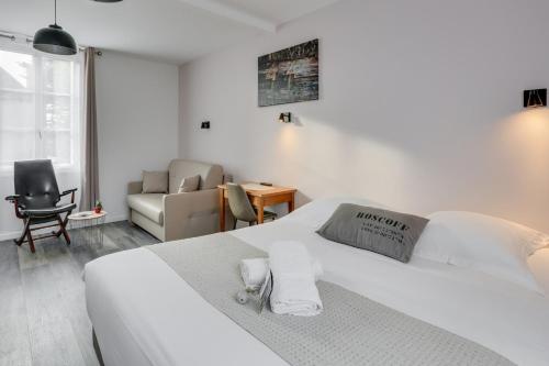 een witte slaapkamer met een bed en een bank bij Hotel D'Angleterre in Roscoff