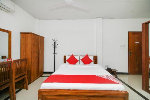 a bedroom with a large bed with red pillows at Grand Rovinka Hotel in Dehiwala