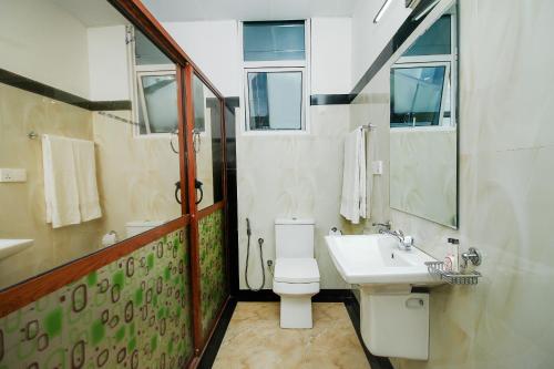 a bathroom with a white toilet and a sink at Grand Rovinka Hotel in Dehiwala