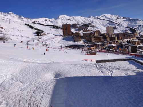 une piste de ski enneigée avec une ville en arrière-plan dans l'établissement Studio Orcières Merlettes Le Christiana, à Orcières