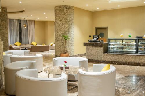 a lobby with white chairs and tables and a cafeteria at Millennium Makkah Al Naseem in Makkah