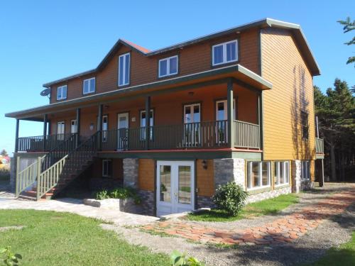 a large brick house with a porch and balcony at Gîte La Maison Chez J.P. Bed and Breakfast in Havre aux Maisons