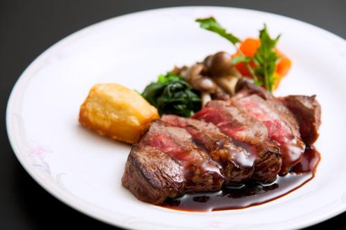 a white plate of food with meat and vegetables at Hotel Oak Forest in Hakuba