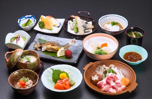 a table topped with bowls of different types of food at Hotel Oak Forest in Hakuba