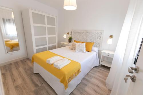 a white bedroom with a large bed with yellow blanket at LA POSADA DE MYA in Villarejo de Salvanés