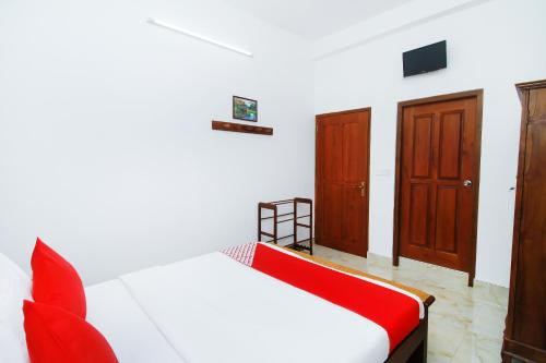 a bedroom with a red and white bed and wooden doors at Ryan Residence & Restaurant in Negombo