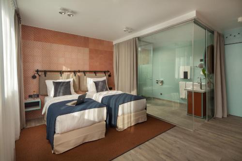 a bedroom with two beds and a glass shower at Cortile Hotel - Adults Only in Budapest