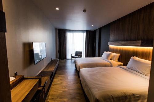 a hotel room with two beds and a television at The Teak Hotel in Mae Sot