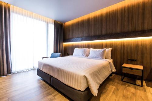 a bedroom with a large bed with a wooden wall at The Teak Hotel in Mae Sot