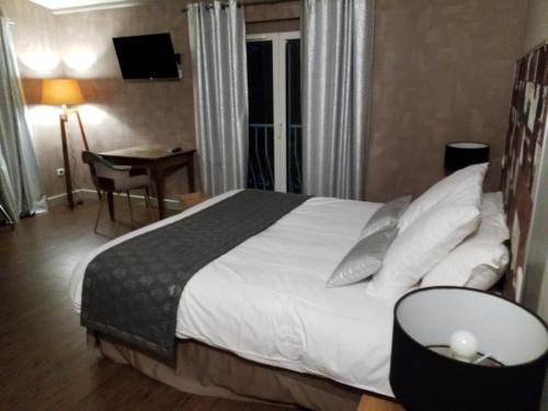 a hotel room with a bed and a table and a desk at Le Cèdre de Soyons in Soyons