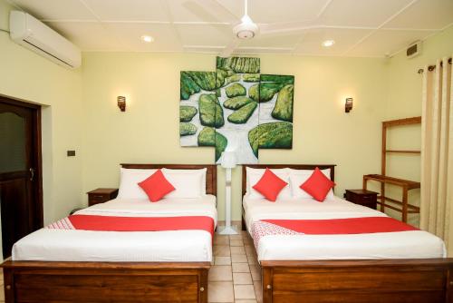 two beds in a room with a painting on the wall at Man Mountain Villa in Matale