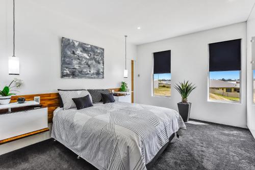 a white bedroom with a bed and two windows at CONROE EXECUTIVE TOWNHOUSE - MODERN & STYLISH in Mount Gambier