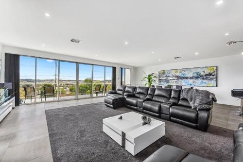 a living room with a leather couch and a table at CONROE EXECUTIVE TOWNHOUSE - MODERN & STYLISH in Mount Gambier