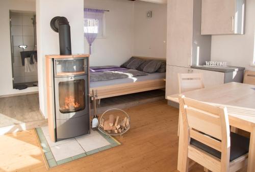a living room with a stove with a bed in the background at Winter´s Panoramahäuschen in Sankt Kathrein am Offenegg