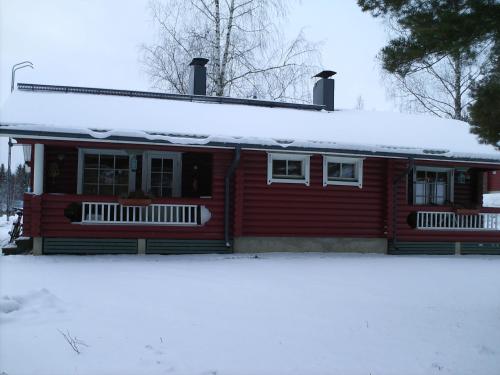 a red house with snow on the roof at Pankkotupa 8B in Punkaharju