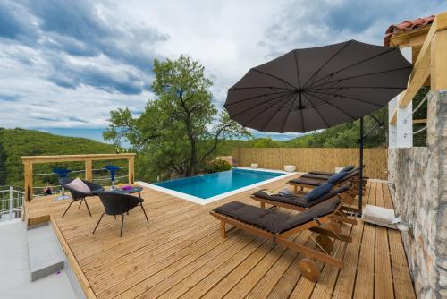 a deck with chairs and an umbrella next to a pool at Villa Dundo Pero in Babino Polje