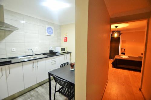 a kitchen with a sink and a table with chairs at Suites & Apartments - DP Setubal in Setúbal