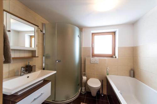 a bathroom with a tub and a toilet and a sink at Appartement Wilder Kaiser in Kitzbühel