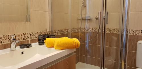 a bathroom with a sink and a shower with yellow towels at Alpe-Adria Apartment Chanel (Top 6 mit Garten) in Oberaichwald