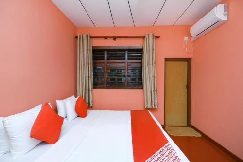 Habitación con cama con paredes de color naranja y ventana. en Sea Beach Inn en Maha Induruwa