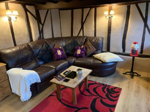 a living room with a leather couch and a table at Myrtle cottage in Dickleburgh