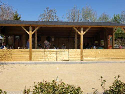 een houten paviljoen met mensen aan tafel bij Camping De Grienduil in Nieuwland