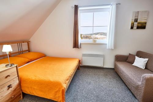 ein Schlafzimmer mit einem Bett, einem Sofa und einem Fenster in der Unterkunft Apartmány Happy Klínovec in Loučná pod Klínovcem