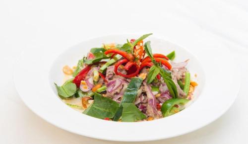 a salad in a white bowl on a white table at Bayon Modern Residence in Siem Reap