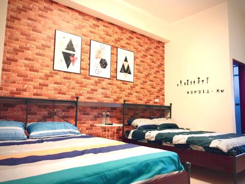 a bedroom with two beds and a brick wall at Chu House in Donggang