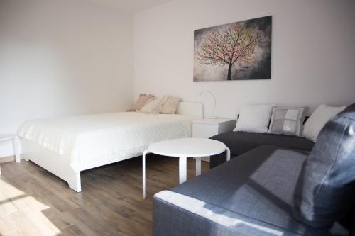 a white bedroom with a bed and a couch at Apartament Kameralny in Kazimierz Dolny