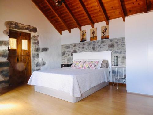 Atlantis Country House في كالهيتا: غرفة نوم بسرير ابيض وجدار حجري