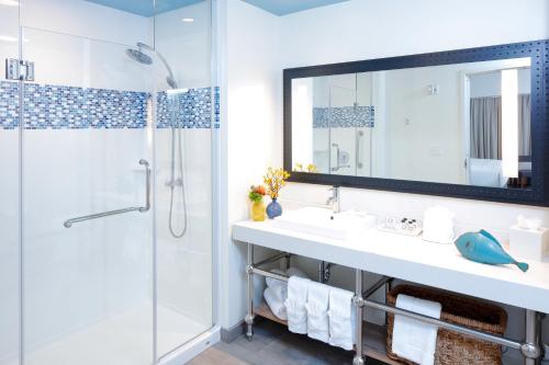 a bathroom with a sink and a shower and a mirror at Hotel Indigo Orange Beach - Gulf Shores, an IHG Hotel in Gulf Shores