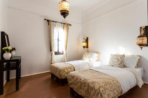 a bedroom with two beds and a table and a window at Kasbah Caracalla in Aghmat