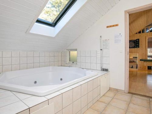a large white bath tub in a bathroom with a skylight at 12 person holiday home in R dby in Kramnitse