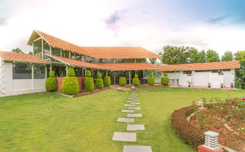 a house with a grass yard with a pathway at Fiestaa Resort n Events Venue in Devanahalli-Bangalore