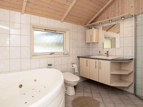 a bathroom with a tub and a toilet and a sink at Three-Bedroom Holiday home in Rødby 38 in Kramnitse