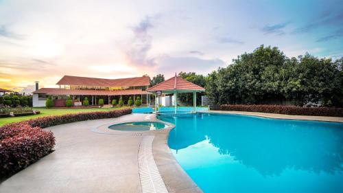 a large blue swimming pool with a gazebo at Fiestaa Resort n Events Venue in Devanahalli-Bangalore